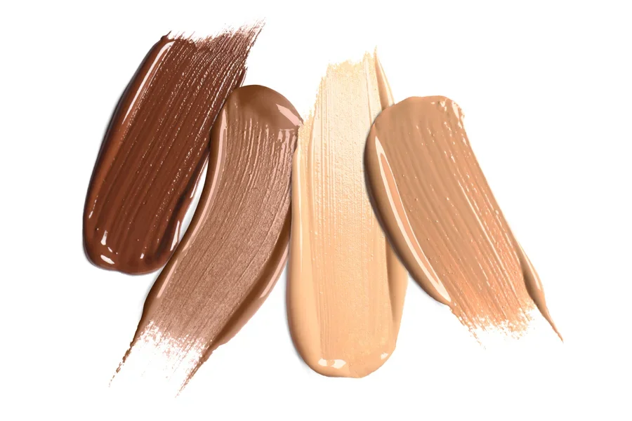 Four different colors of liquid foundation brushes onto white surface