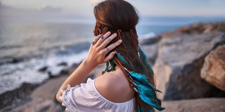 Hippie Indie Woman with Blue Feathers in Hair on The Seashore
