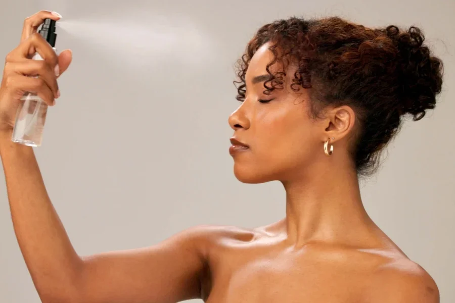 Makeup enthusiast using setting spray mist on face