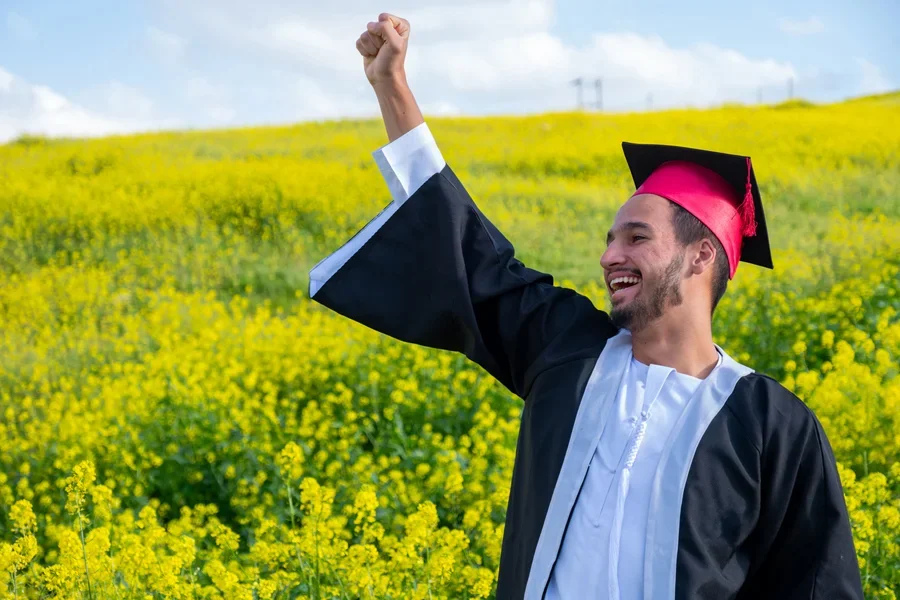 Hombre de pie en el campo con una gorra de graduación hecha a mano