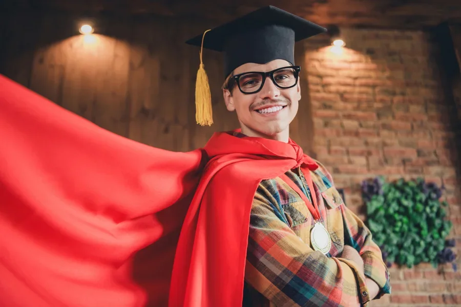 Hombre con gafas, birrete de graduación y capa roja