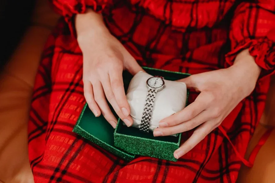 Seseorang Memegang Kotak Hijau Berisi Jam Tangan Perak di Dalamnya