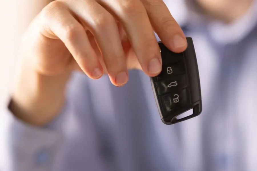 Salesperson is giving car key to the new owner in a dealership