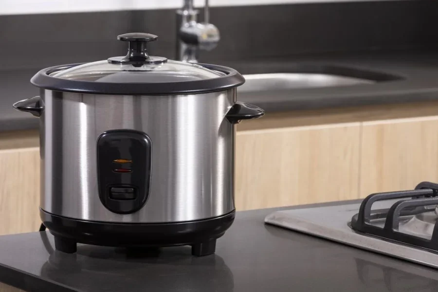Small electric rice cooker on kitchen background