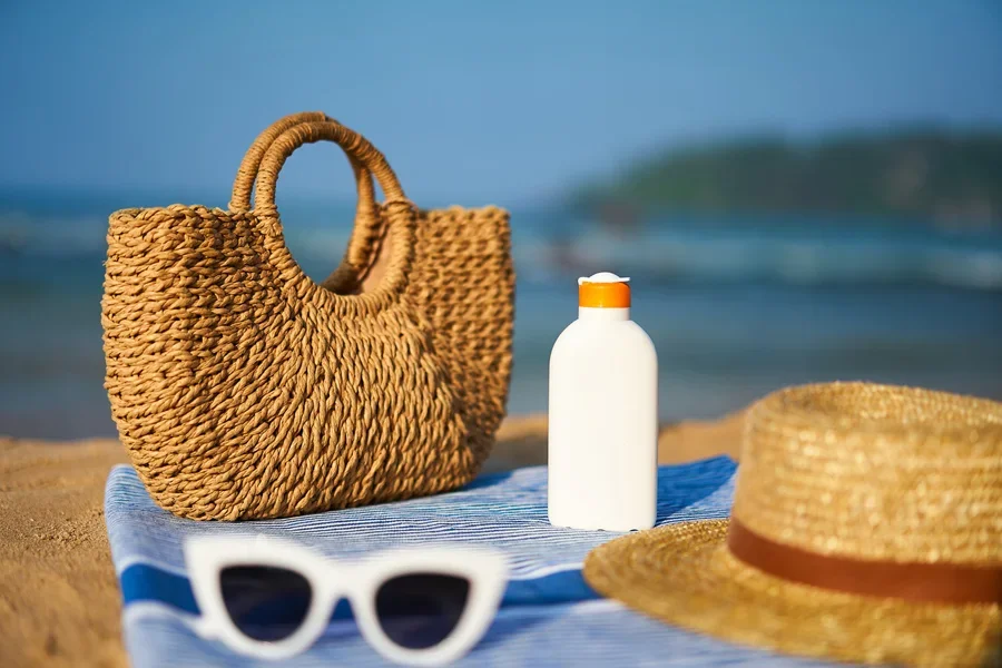 Petit sac de plage en raphia posé sur une serviette bleue lors des journées à la plage
