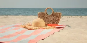 Straw beach bag on towel next to straw sun hat