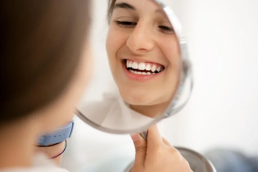 Teenage girl looking at her teeth in the mirror