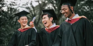Three people wearing male graduation caps on campus
