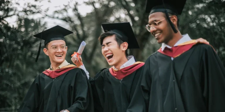 Three people wearing male graduation caps on campus