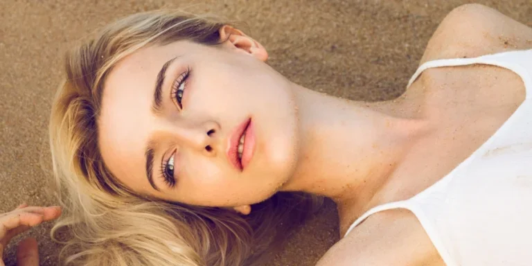 Frau mit sandblondem Haar liegt am Strand