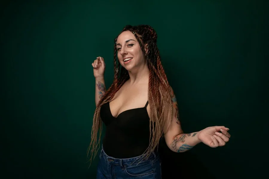 Woman With Dreadlocks Standing in Front of Green Background
