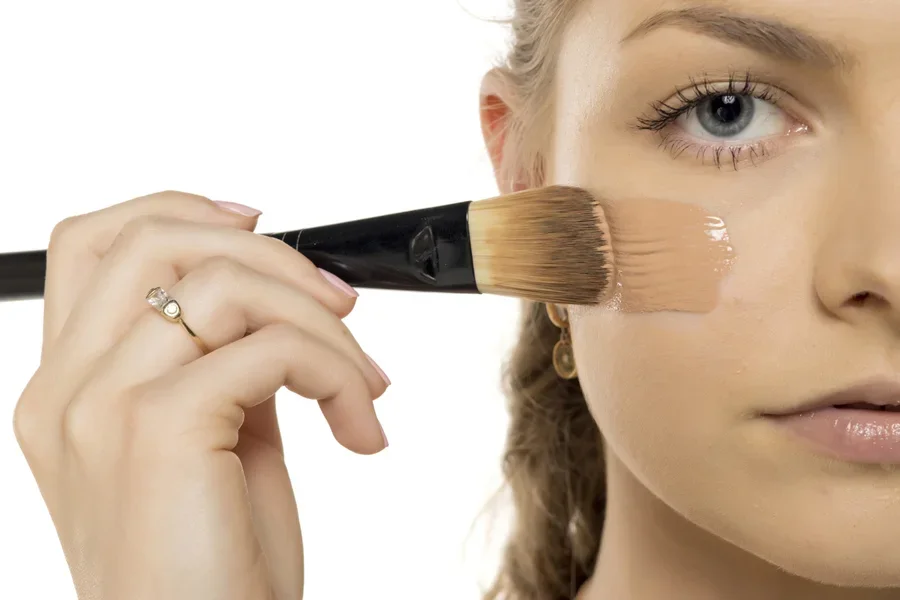 Woman applying creamy concealer to face in darker shade
