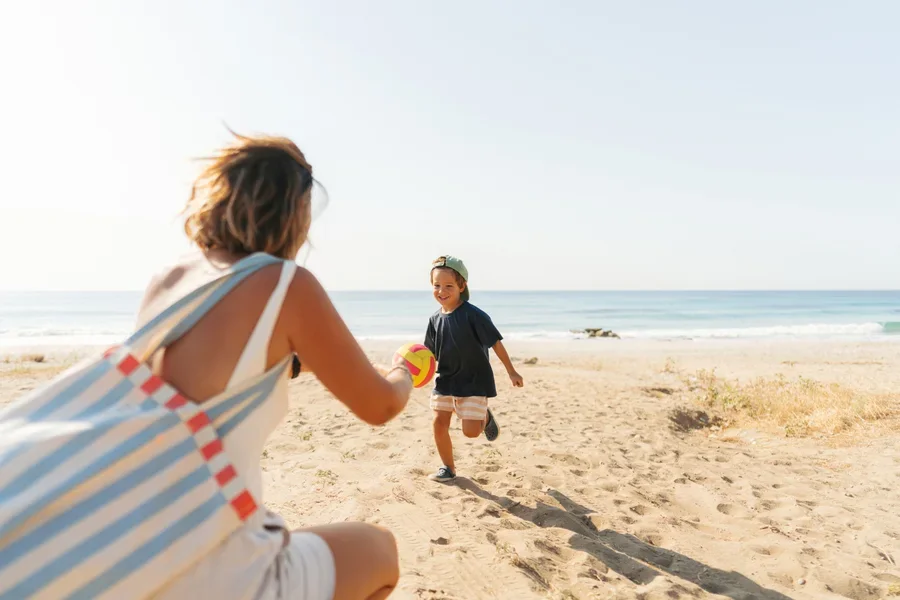 Femme avec un sac de plage en tissu jouant avec son fils sur la plage