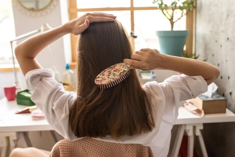 美しい茶色の髪を梳かす若い女性