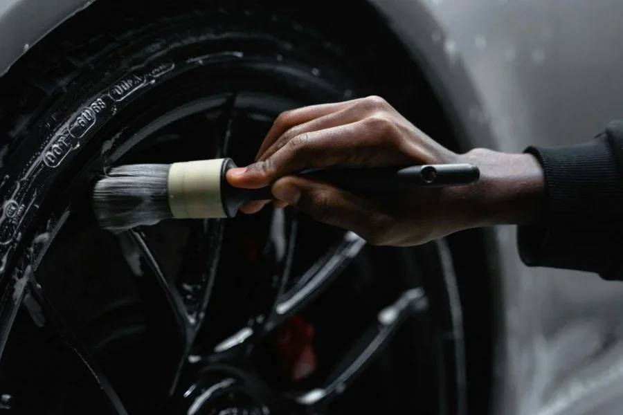 Uma pessoa limpando o pneu de um carro.