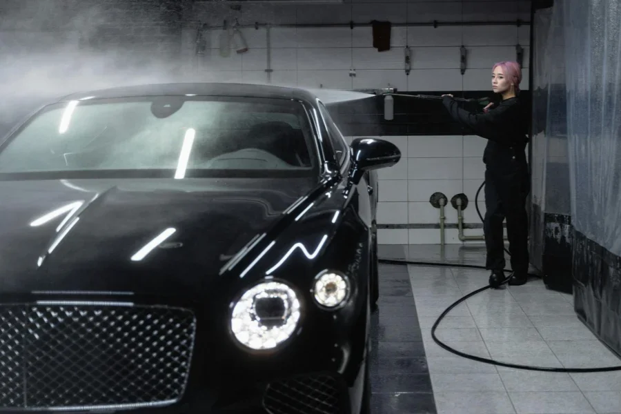 A Woman Washing a Car with a Power Spray