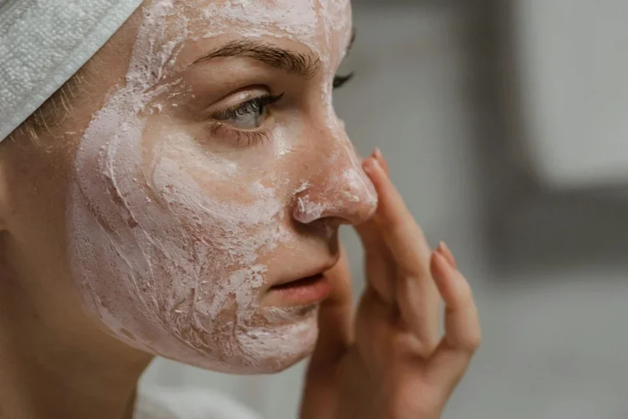 Foto em close-up de uma mulher aplicando creme facial.