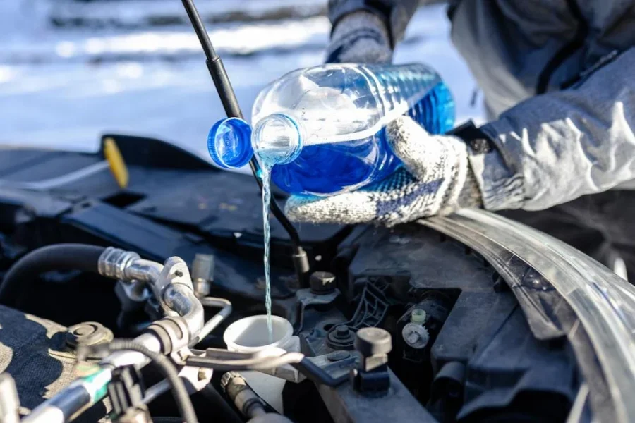 Close up of man hands pouring winter windshield washer fluid into spray tank