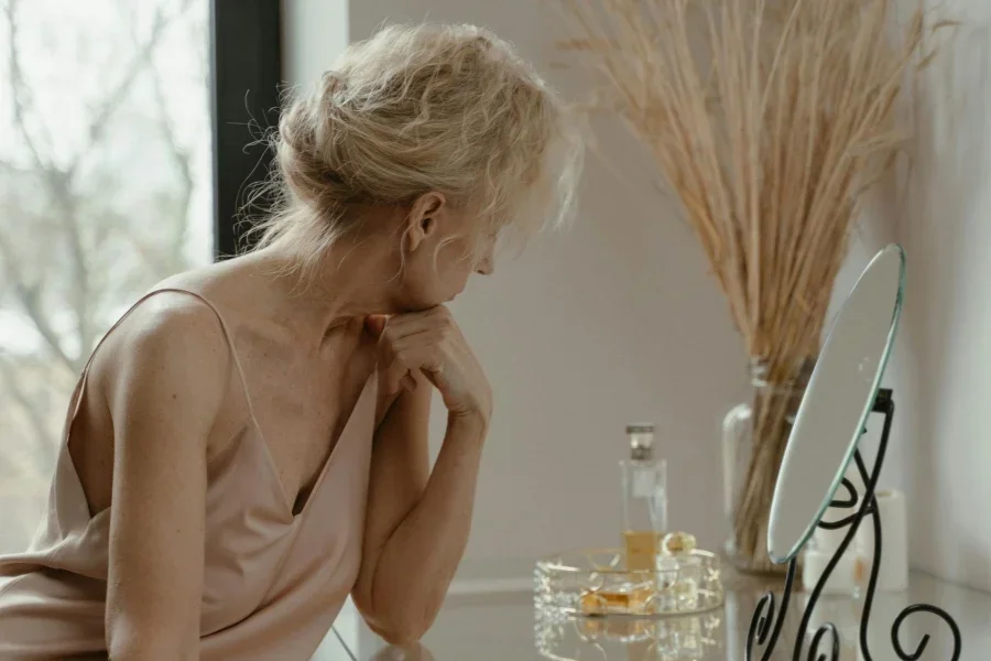 Mulher idosa sentada em frente a um espelho