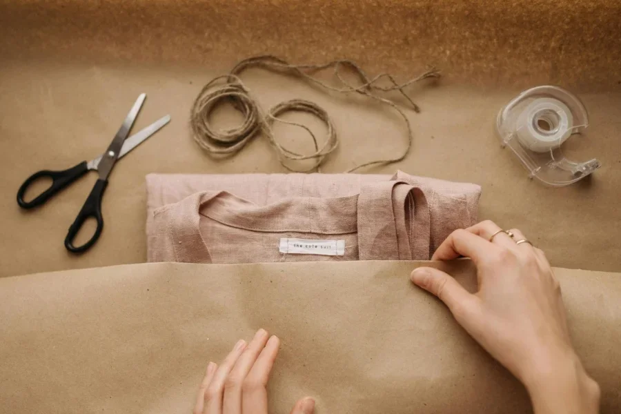 Des mains emballent la chemise sur du papier kraft