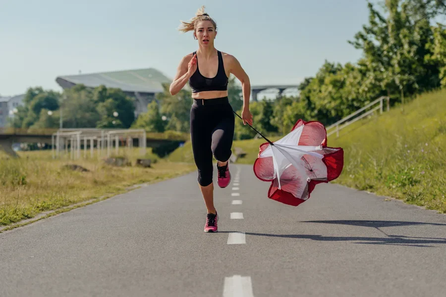 Sportswoman Training in the Park and Running with a Resistance Parachute