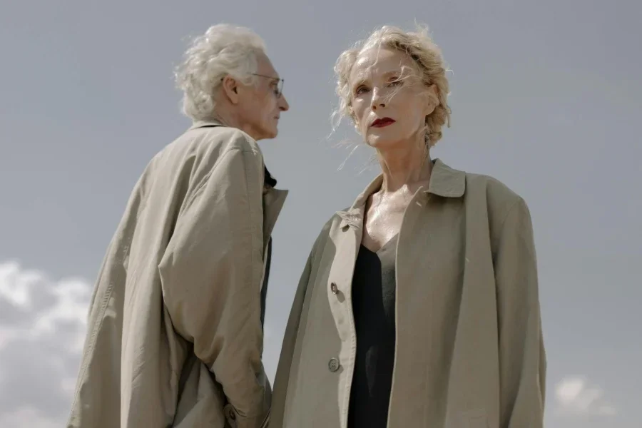 Duas pessoas idosas vestindo capas de chuva marrons