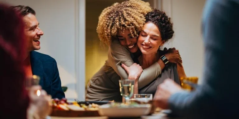 Dos amigos abrazándose durante una cena de celebración